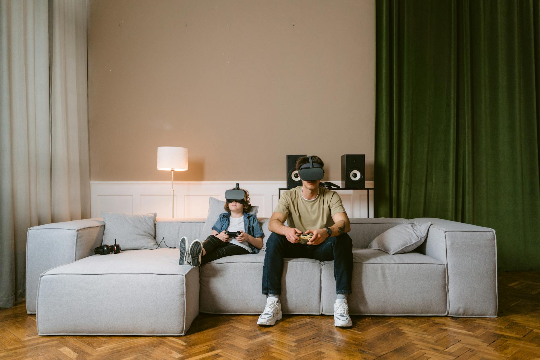 Un homme et un enfant appréciant des jeux vidéo avec des casques VR sur un canapé moderne à la maison.