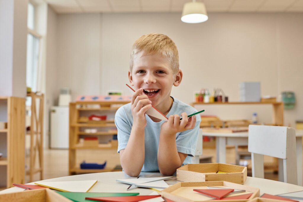 Boy gai qui tient des triangles pendant le jeu en classe à l'école Montessori