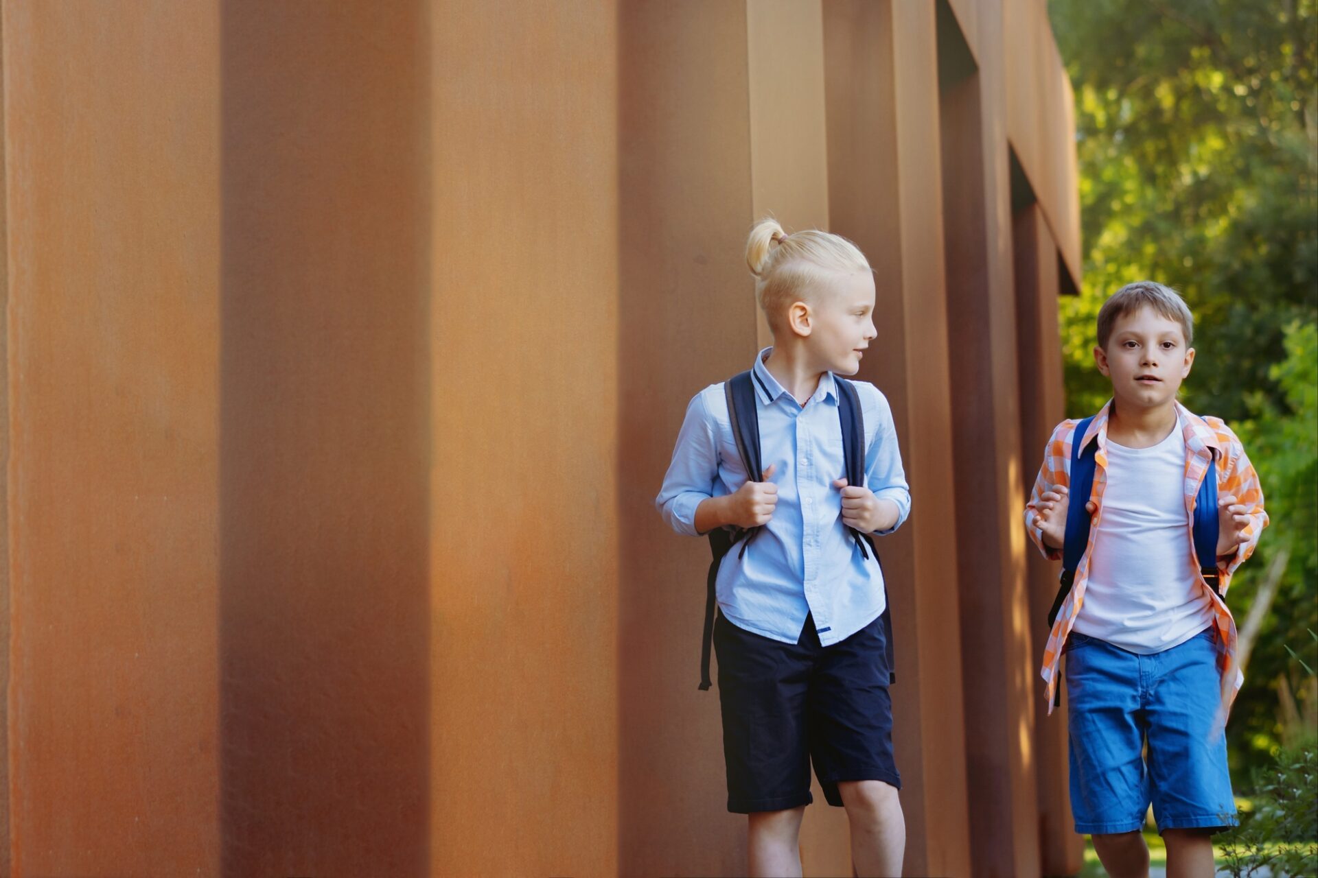 Les enfants vont à l'école avec des sacs à dos le jour ensoleillé. 
