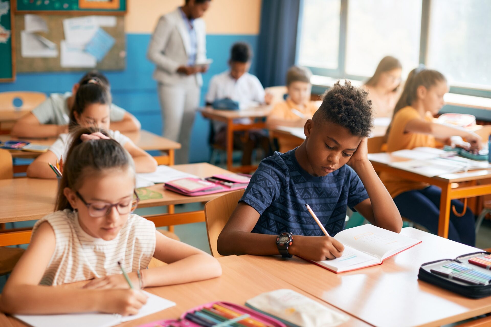 Écolier afro-américain et ses camarades de classe écrivent pendant un cours à l'école.
